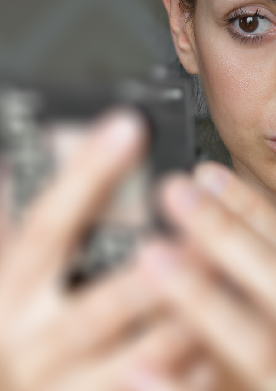 Femme se regardant dans un miroir de poche, illustration du visage comme reflet de l’état du corps et du face mapping