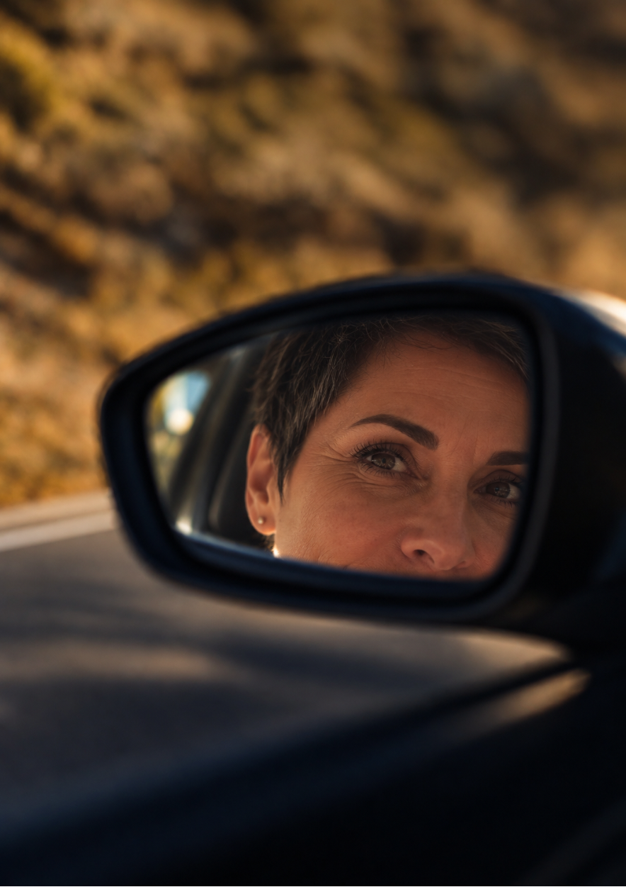 Regard d’une femme dans le rétroviseur d’une voiture, symbole du chemin parcouru et de la dernière ligne droite de l’année